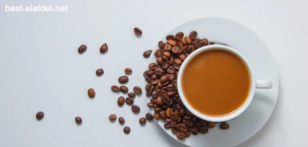 A cup of coffee on a small plate with some coffee beans on it and next to the cup some coffee beans within the talk about the side effects of drinking too much coffee